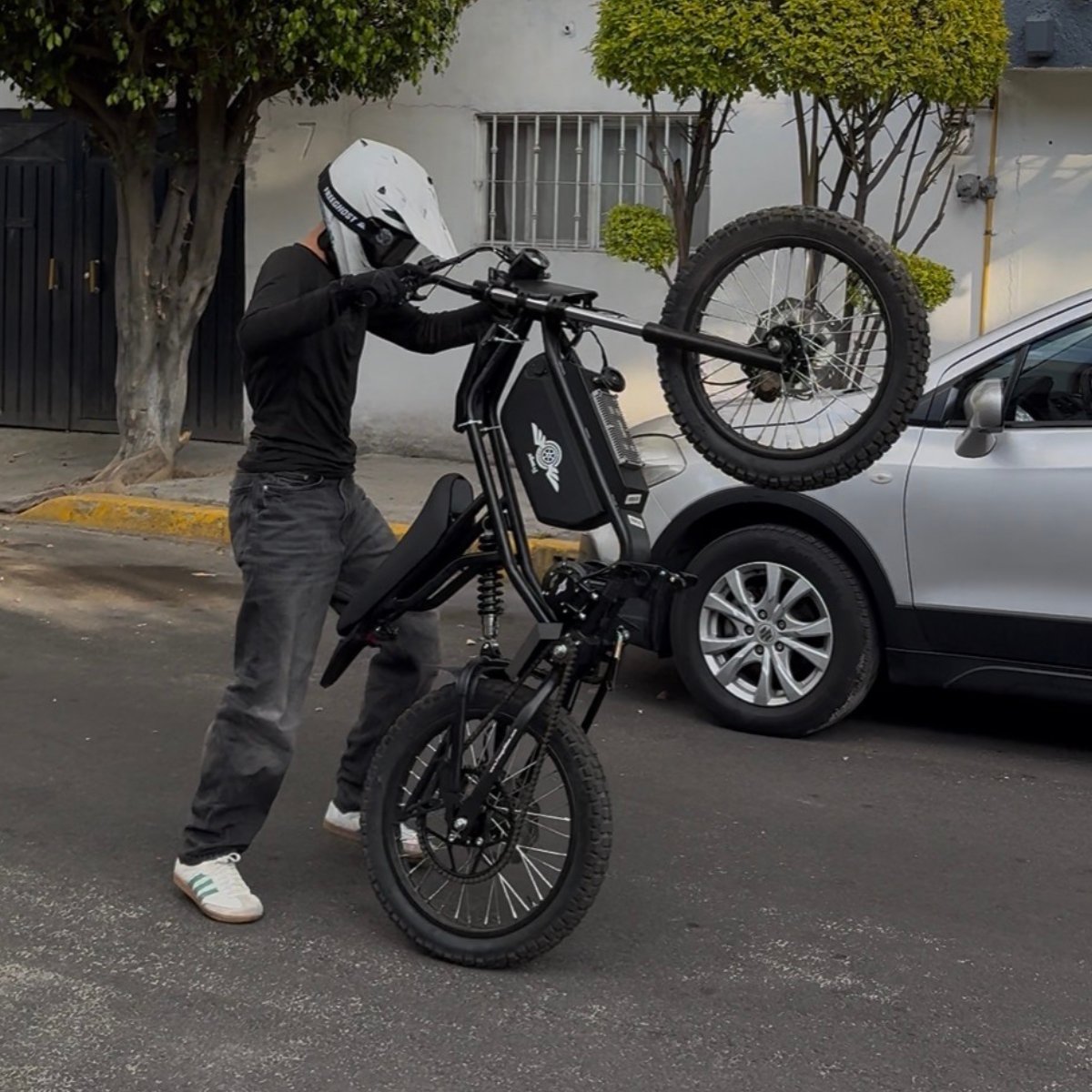 Person lifting a Freego Nova 3 electric bike with a car in the background