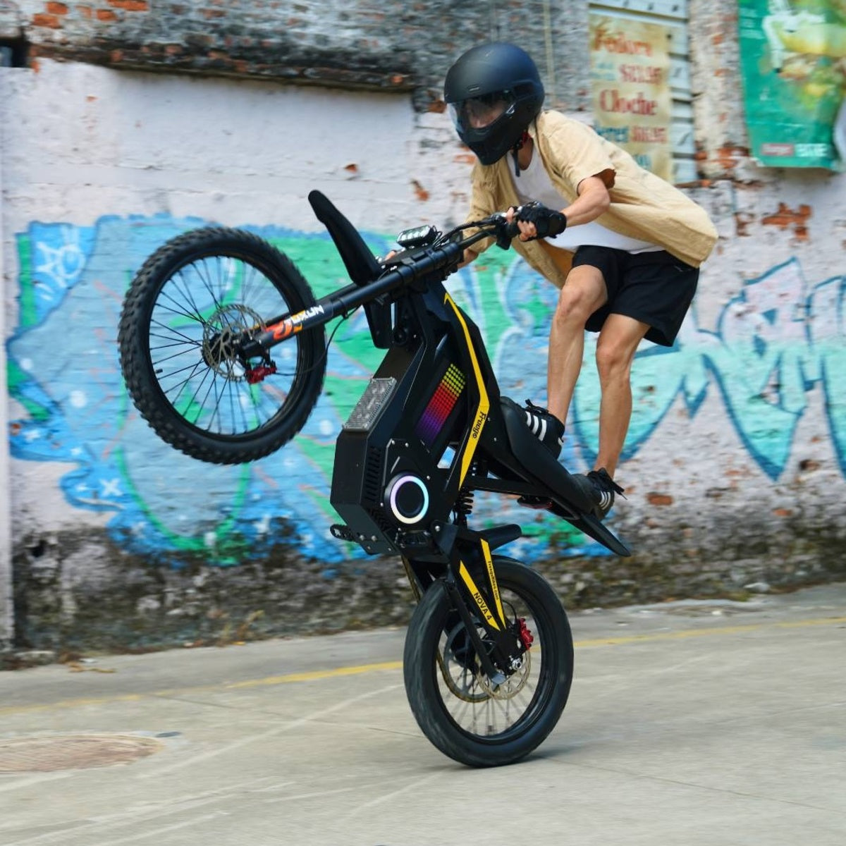 Rider performing wheelie on Freego Nova4 electric dirt bike in urban graffiti setting