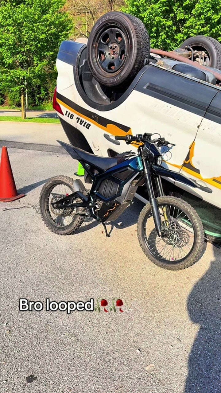 Freego Nova 5 electric dirt bike parked in front of an overturned police car on the street