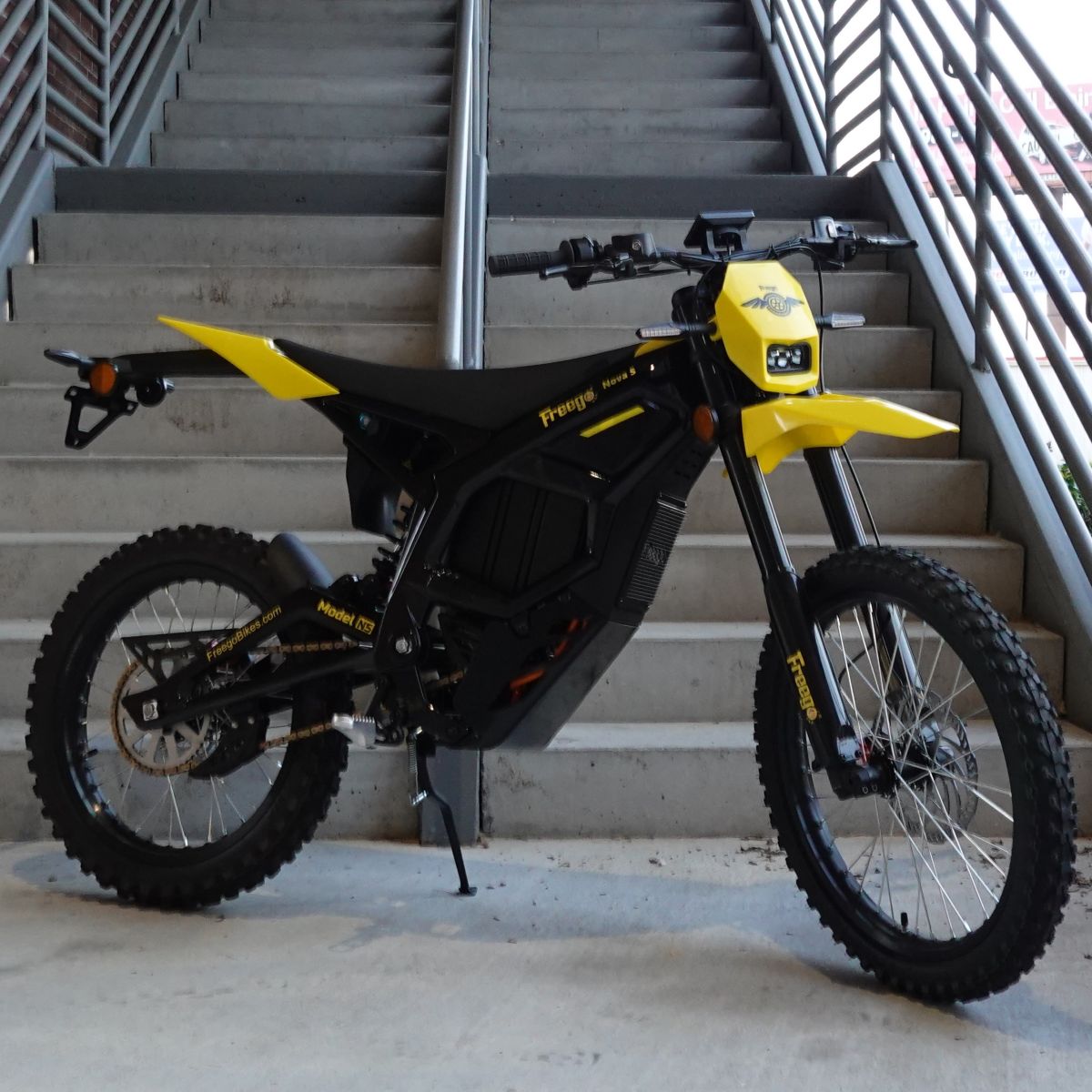 Black and yellow electric bike on a concrete surface with stairs in the background
