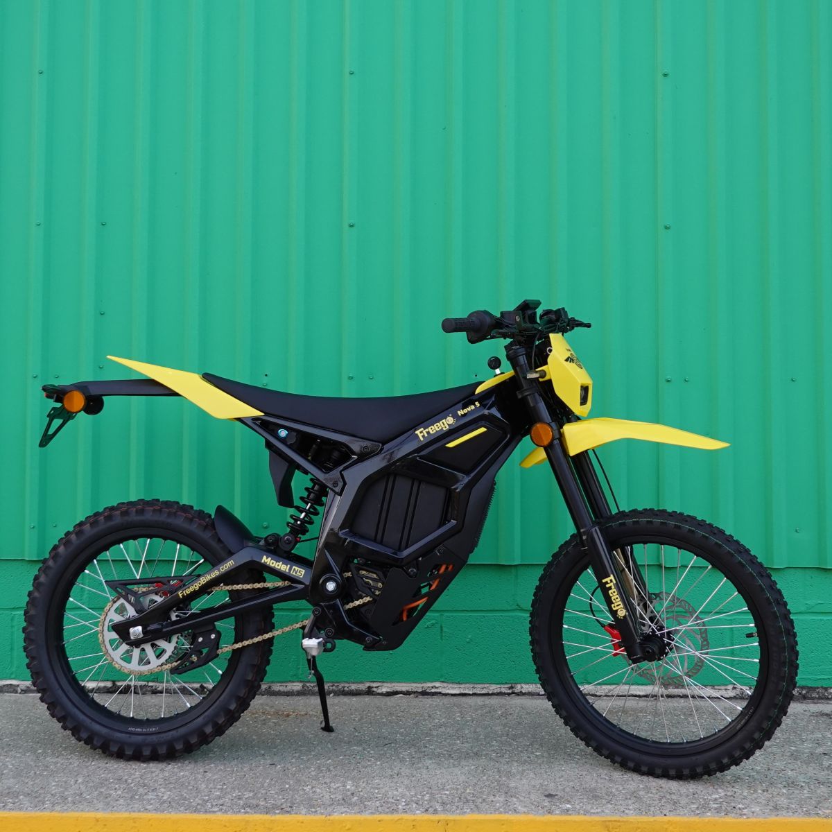 Yellow and black electric bike against a green wall