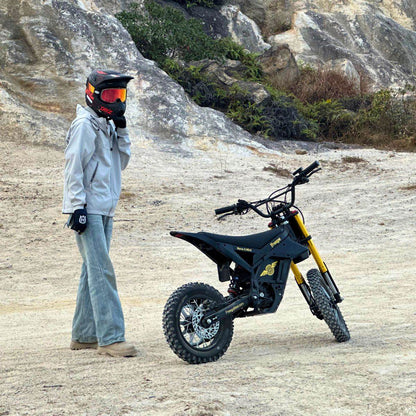 Person with a helmet standing next to a Nova 5 Mini ebike in a rocky outdoor setting
