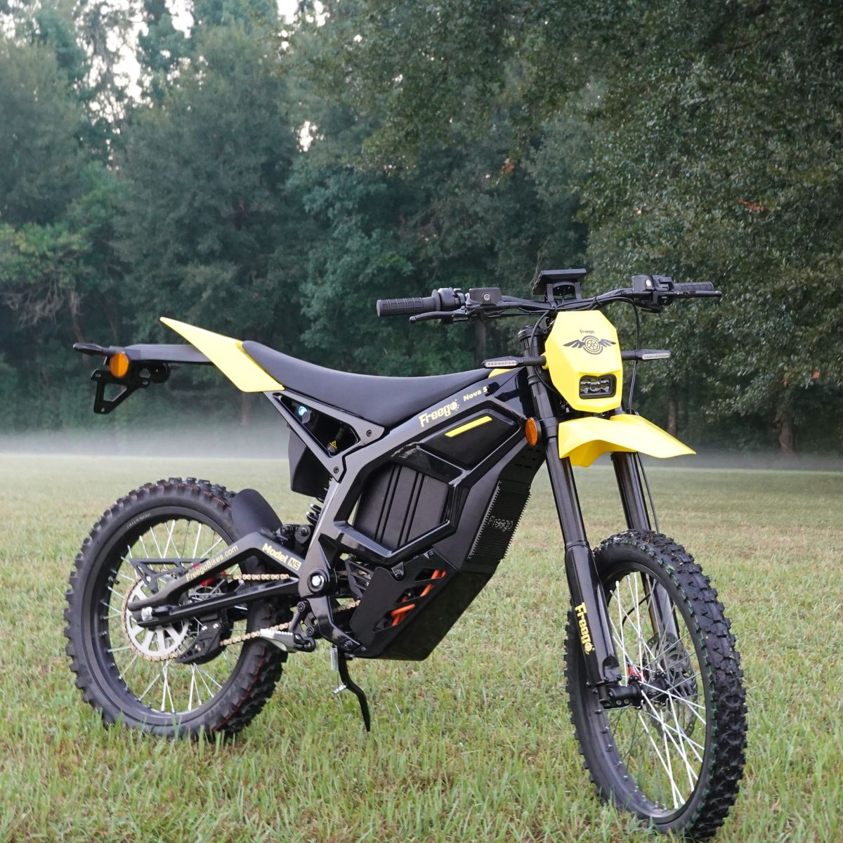 Black and yellow electric bike on grass with trees in the background