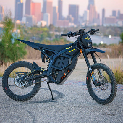 Freego Nova5 electric dirt bike parked on pavement with downtown city skyline at sunset, side view product photo