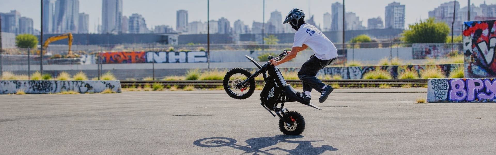 Rider performing a wheelie on the Freego X0 electric moto in an urban setting.