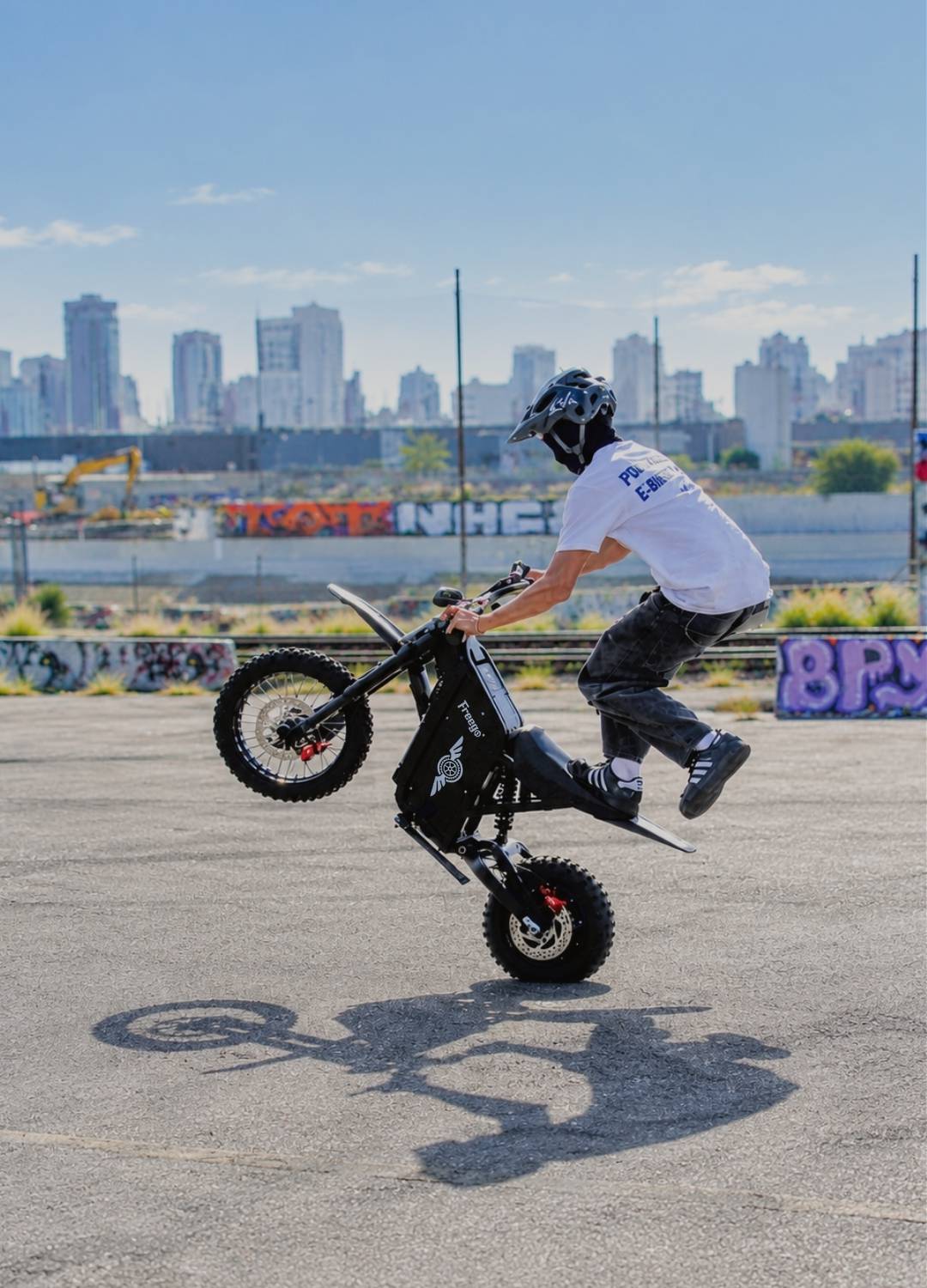 Rider performing a wheelie on the Freego X0 electric moto in an urban setting.