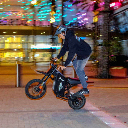 Person riding a Freego X0 Mini ebike on a city street at night with colorful lights in the background