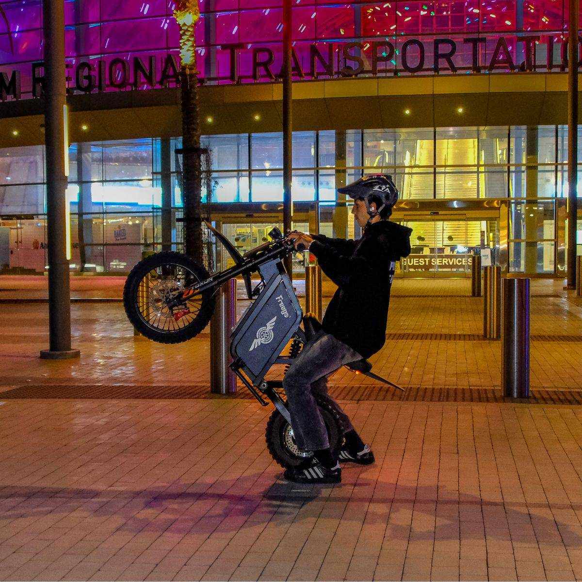 Person with a Freego X0 Mini ebike in front of a building at night