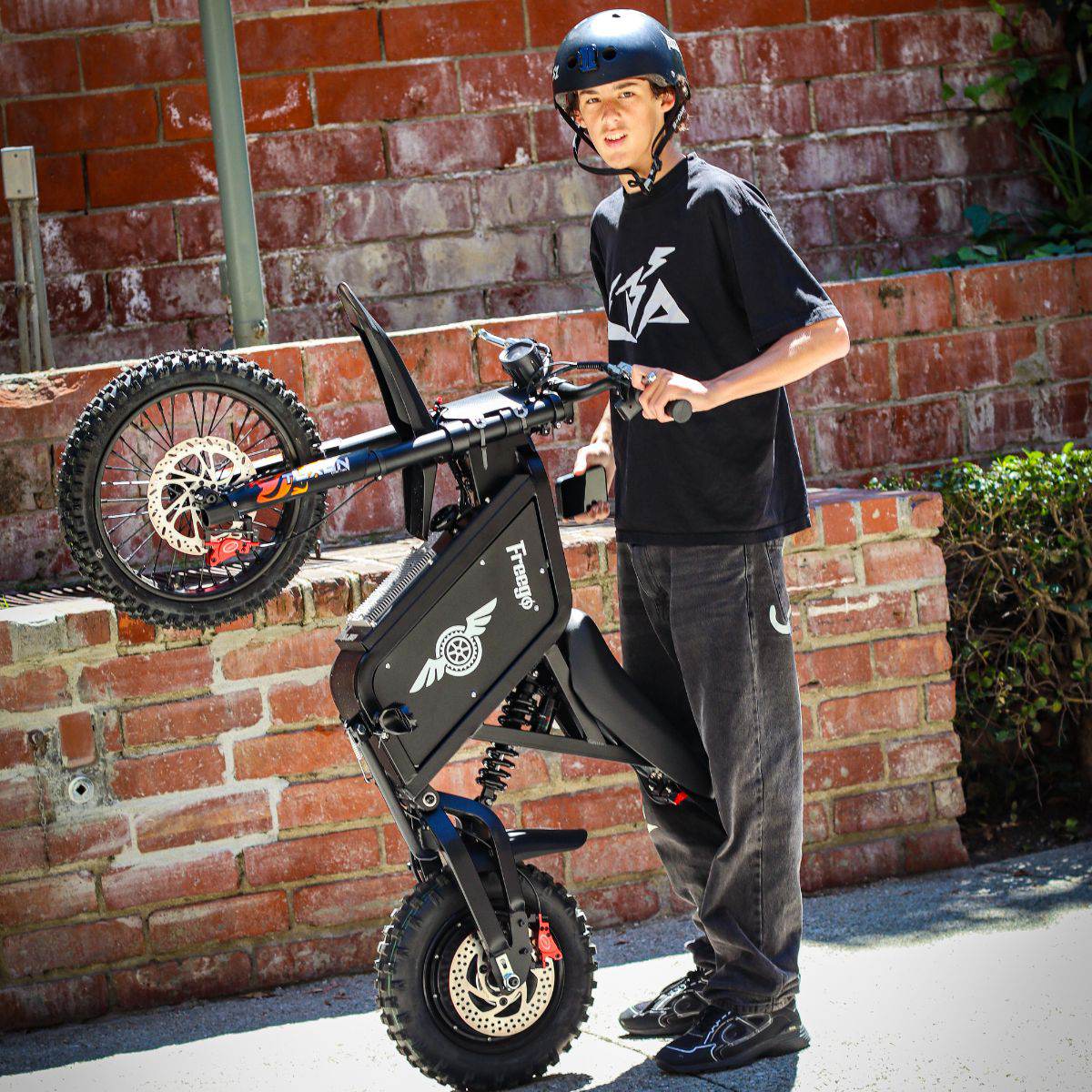 Person standing next to a Freego X0 Mini ebike against a brick wall.