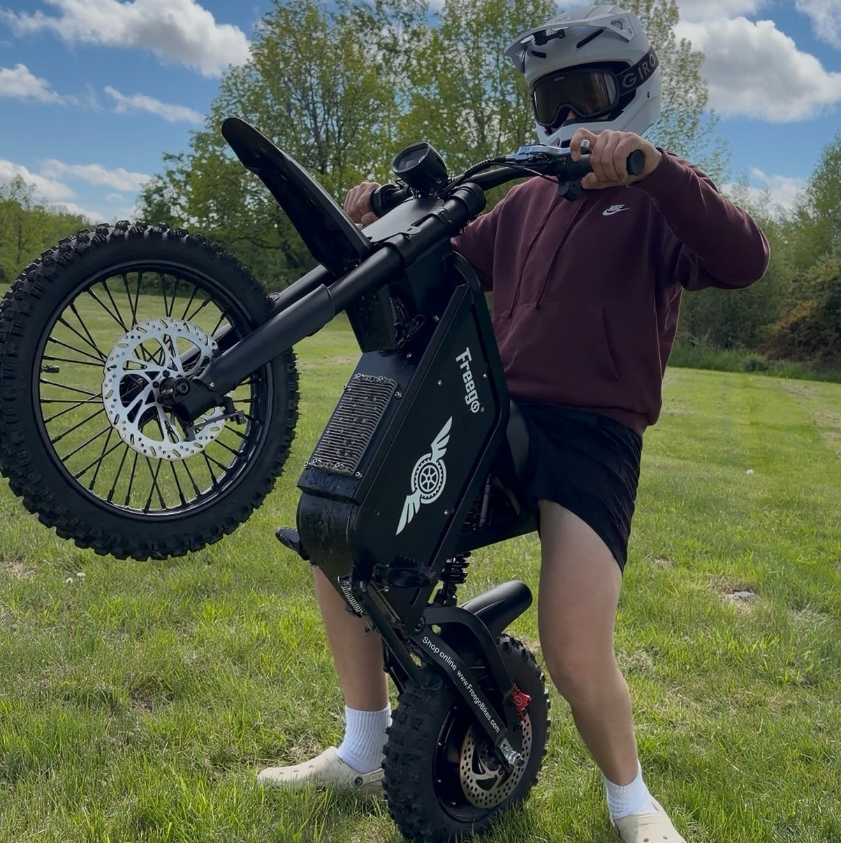 Rider doing wheelie with Freego X0 off road electric dirt bike on grass field