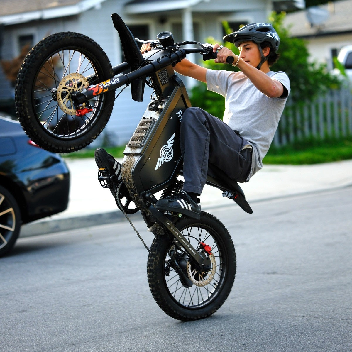 Rider performing a wheelie on the Freego X1 all-terrain electric dirt bike on a city street