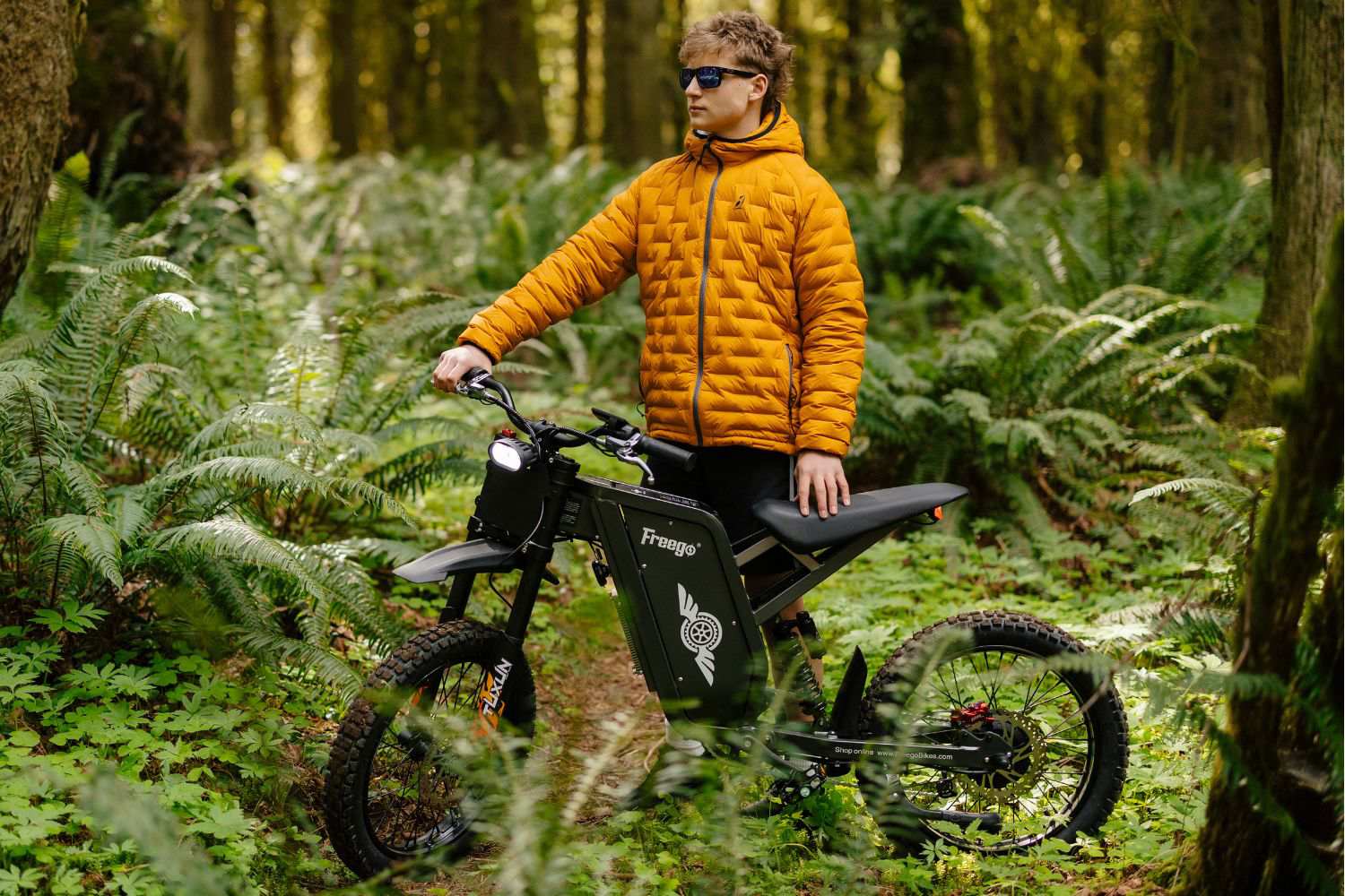 Rider on the Freego X1 electric dirt bike riding through a forest trail.