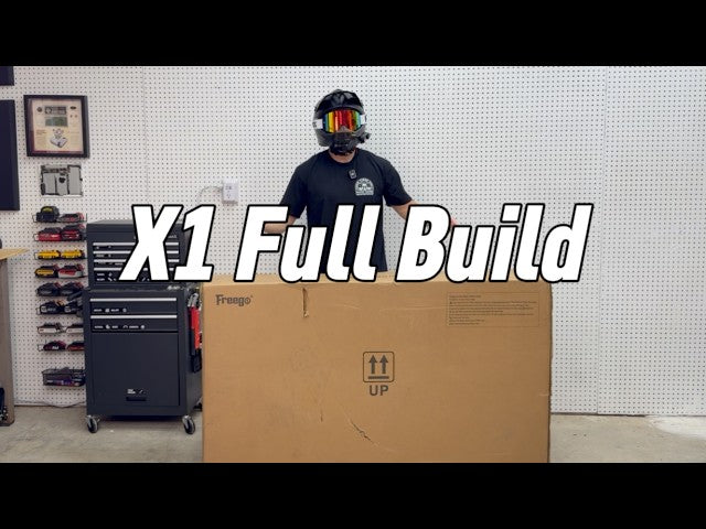 Helmeted rider standing behind a large Freego X1 shipping box in a workshop setting with “X1 Full Build” text overlay.