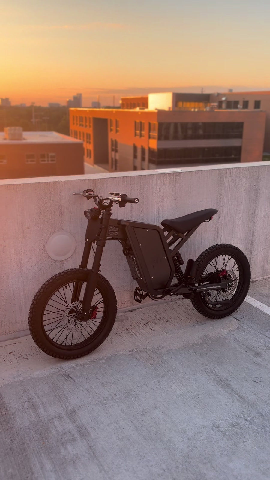 Black Freego X1 fat-tire electric bike on a rooftop at sunset.