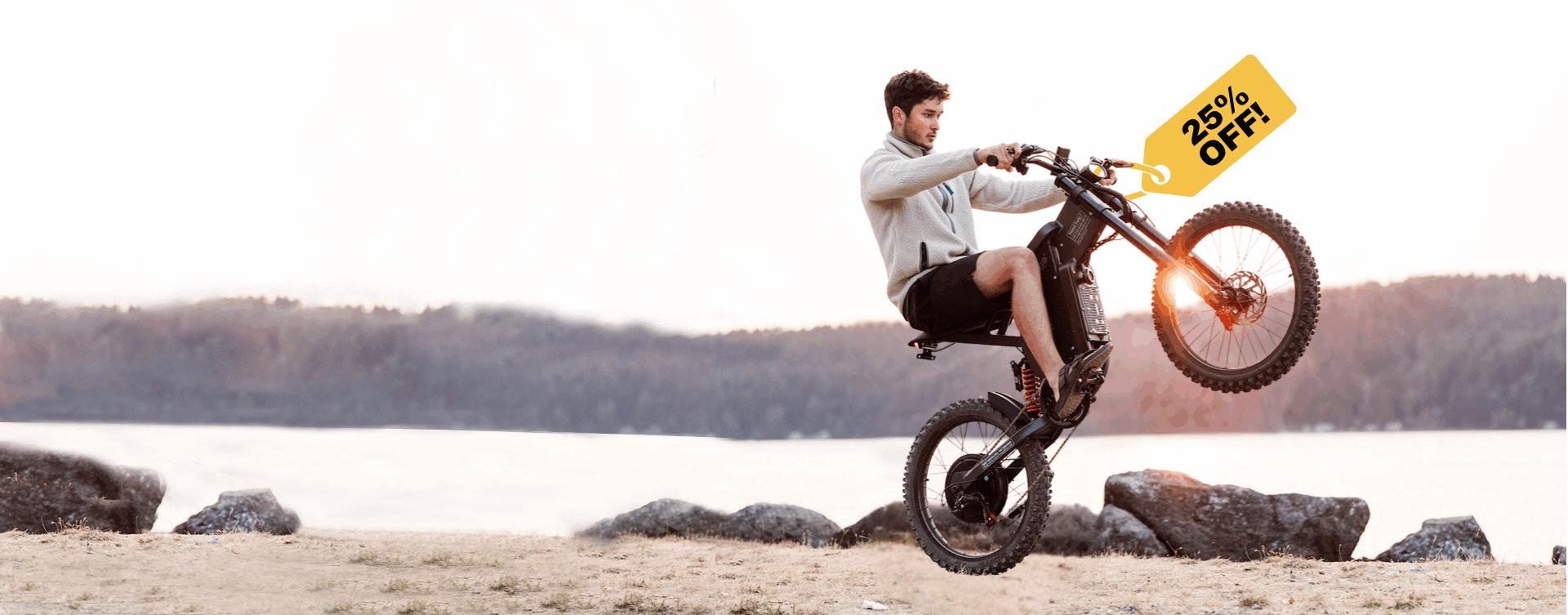 Man riding a X2 ebike on a beach with a promotional sign above him.