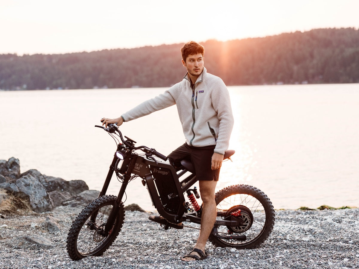 Man standing next to a Freego X2 dirt bike by a lake