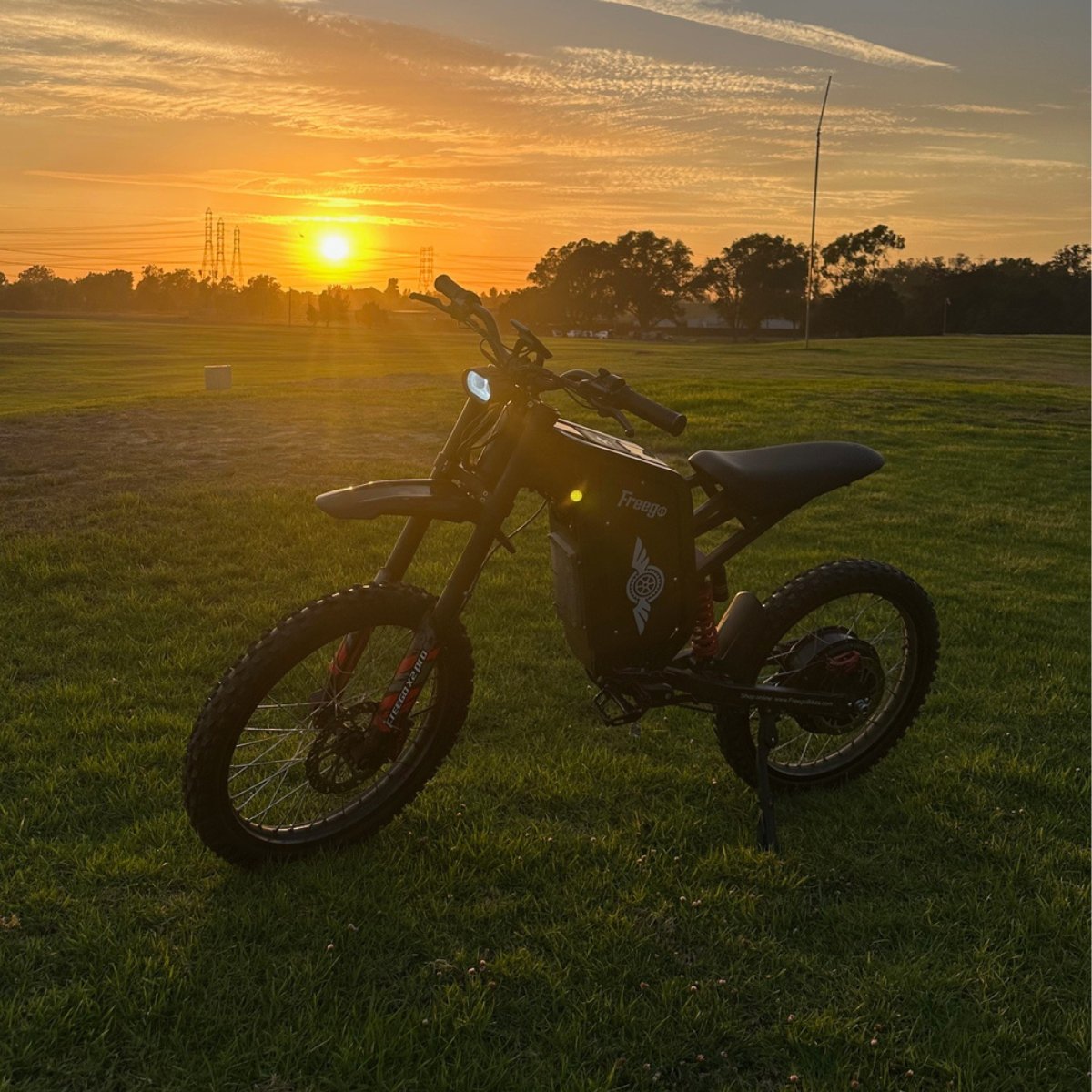 The X2 Pro dirt bike on a grassy field with a sunset in the background