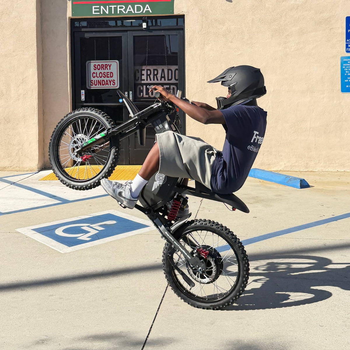 Helmeted rider performing a seated wheelie on a Freego X2 Pro electric bike.