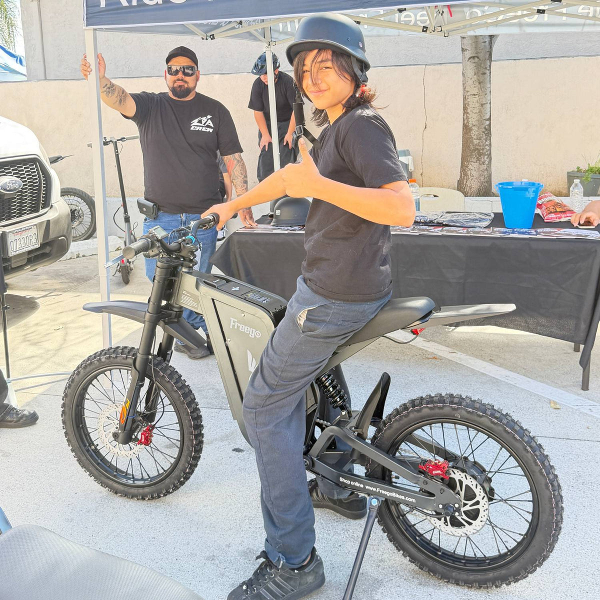Helmeted rider sitting on a Freego X2 Pro electric dirt bike at an outdoor event.