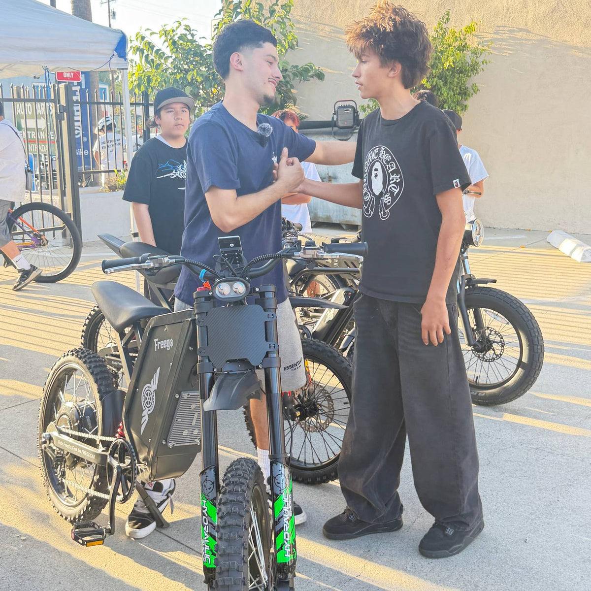 Riders greeting each other beside Freego X2 Pro electric dirt bikes at an outdoor meetup.
