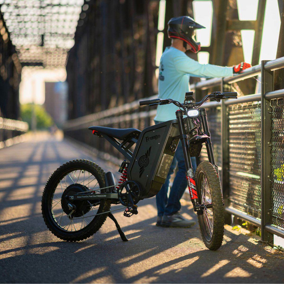 Person with a Freego X2 Pro dirt ebike on a bridge during sunset