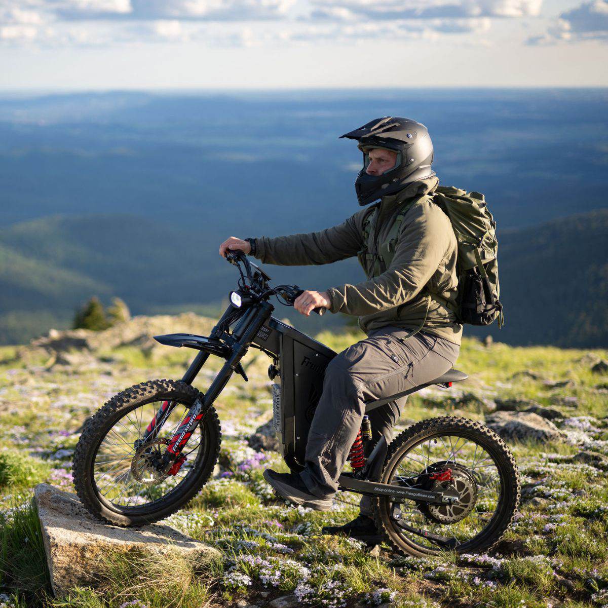 Person riding a Freego X2 Pro dirt ebike on a mountain with a scenic view in the background