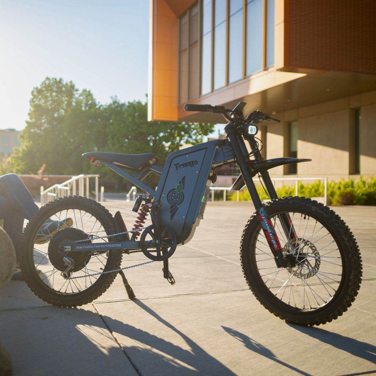 A Freego X2 Pro dirt ebike parked on a sidewalk with a modern building in the background
