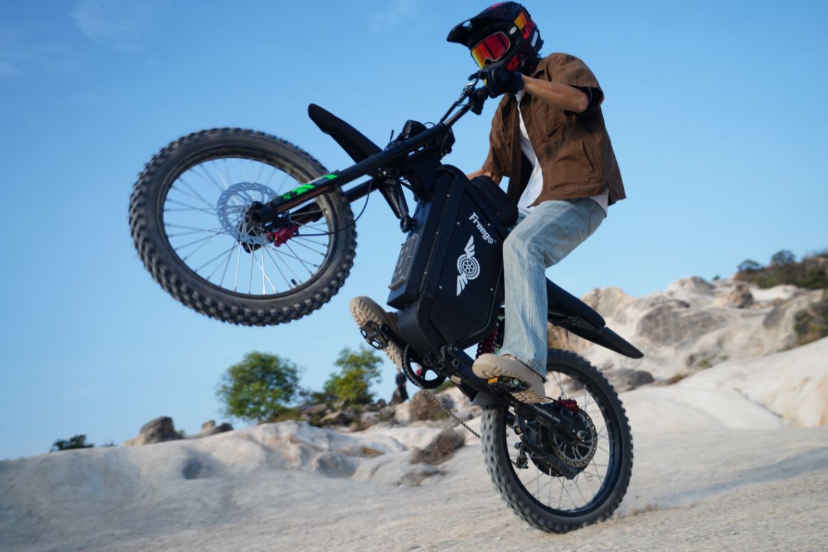 A person riding the Freego X3 dirt e-bike with pedals outdoors on a trail