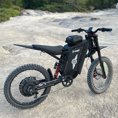 Freego X3 electric dirt bike (with pedals) sits on expansive bare rocky terrain; brand logos, rugged tires, and chain/pedal system clearly visible.