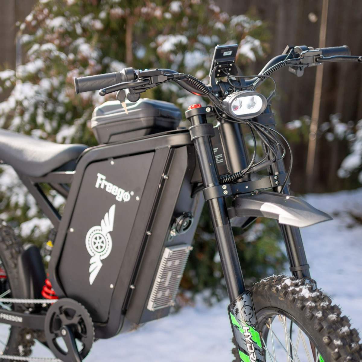 A close-up of the battery at the right front angle of the freego x3 with snow on trees in the background.