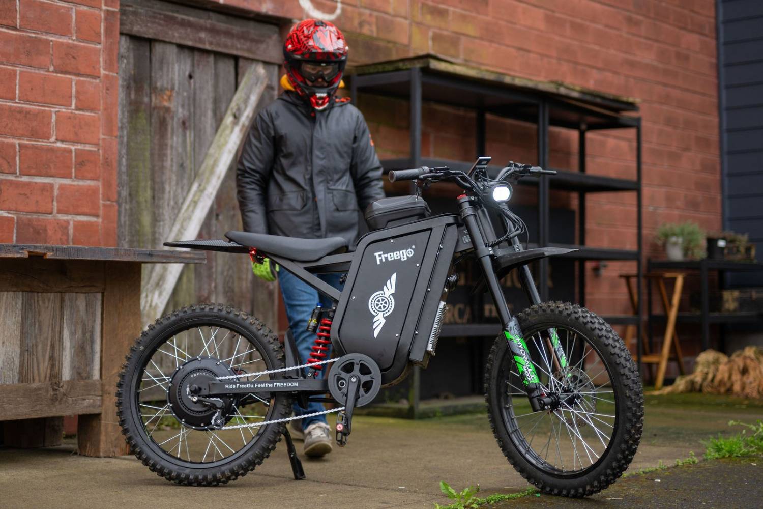 Freego X3 Pro electric dirt bike viewed from the side near a brick wall.