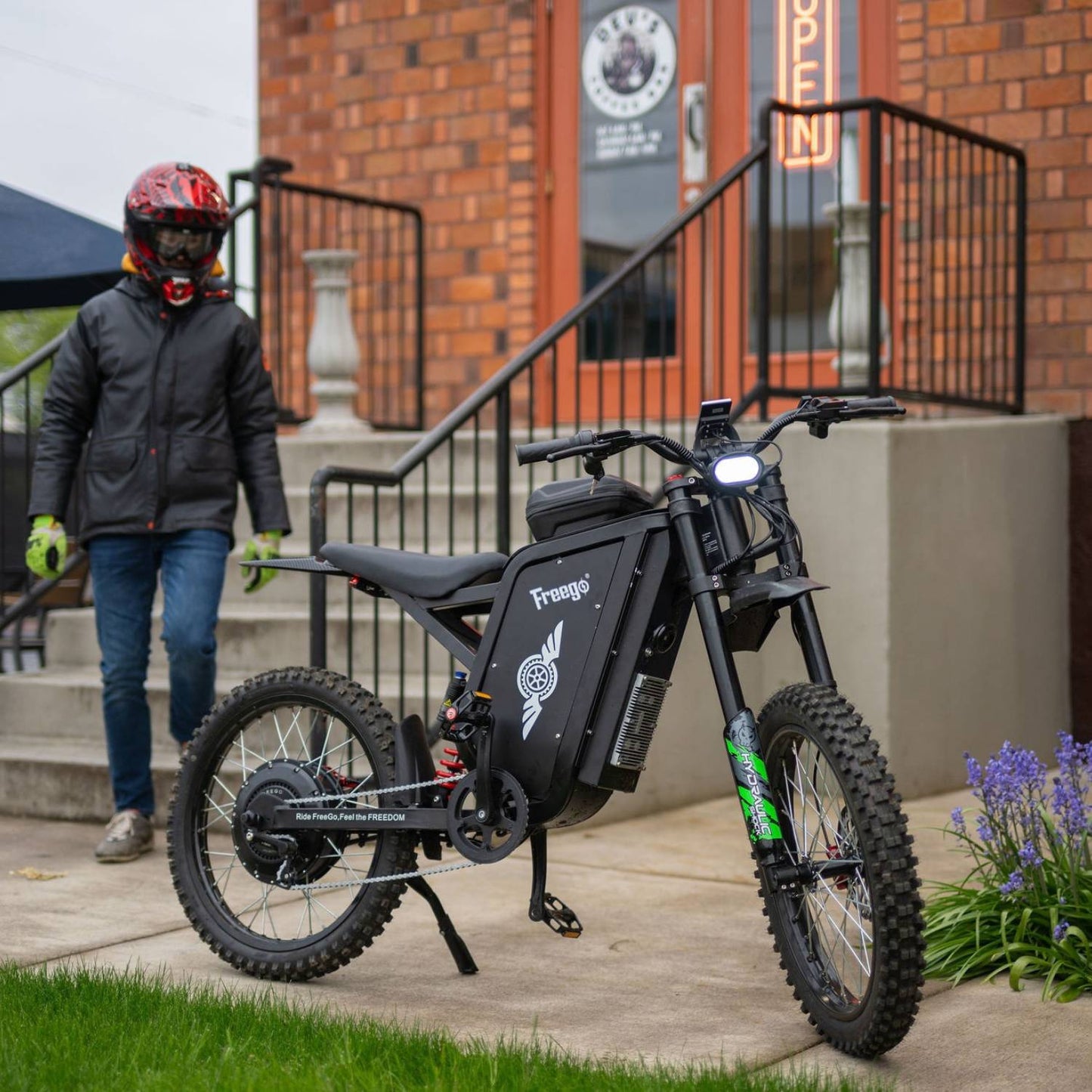 Rider standing with the Freego X3 Pro electric dirt bike in an urban scene.
