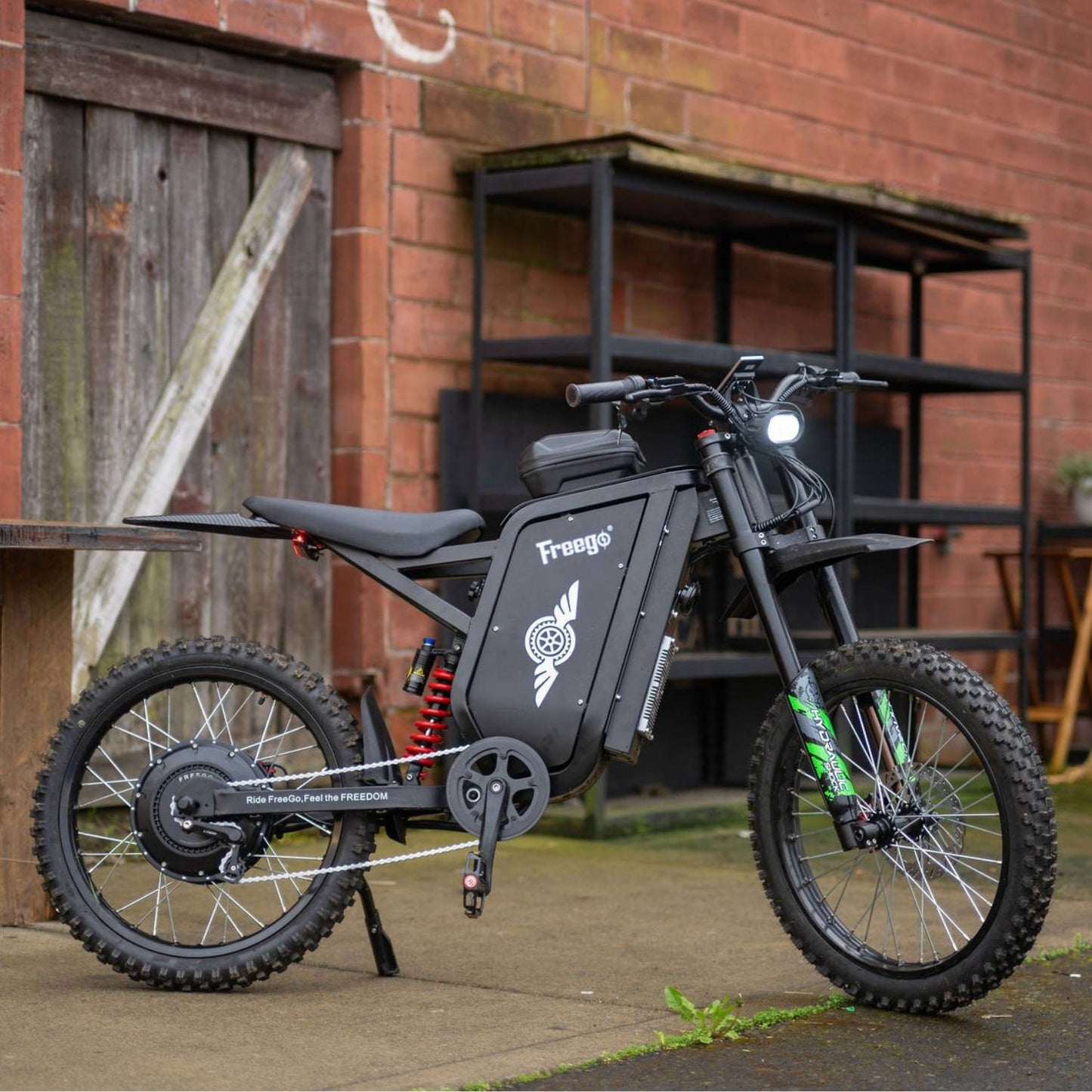 Freego X3 Pro electric dirt bike viewed from the side in an industrial setting.