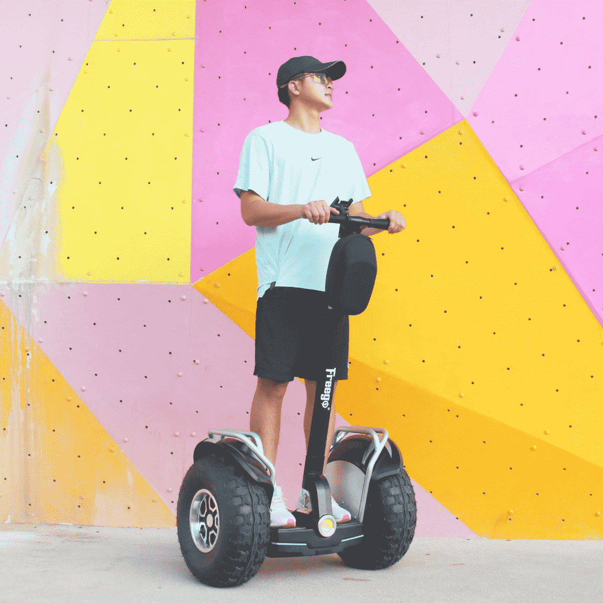 Person standing on a hoverboard against a colorful geometric wall.