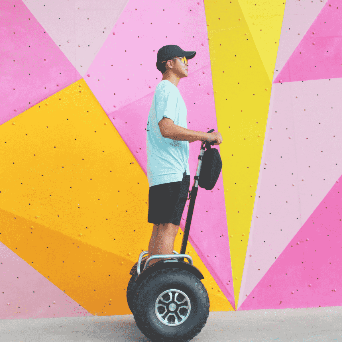 Person riding a segway against a colorful geometric wall.