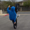 Person in a blue hoodie performing a wheelie on bicycle in an outdoor setting.