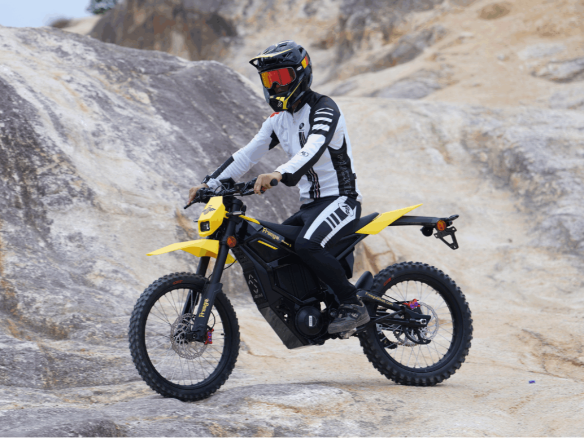 Person riding a yellow electric bike on rocky terrain